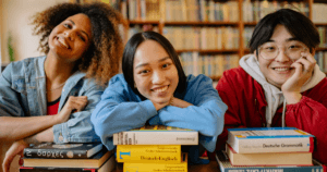 A group of college students smiling and leaning on their books to represent Education Grants