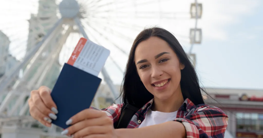 A student smiling and holding up her passport to represent statement of Purpose (SOP)