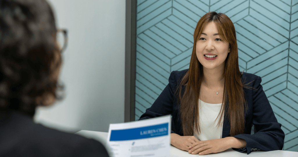 Two women in an office sitting for a Visa Interview